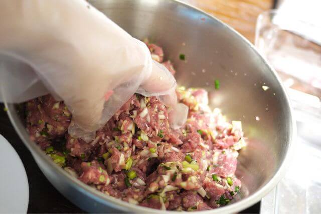 手袋をした手が材料を混ぜ合わせる